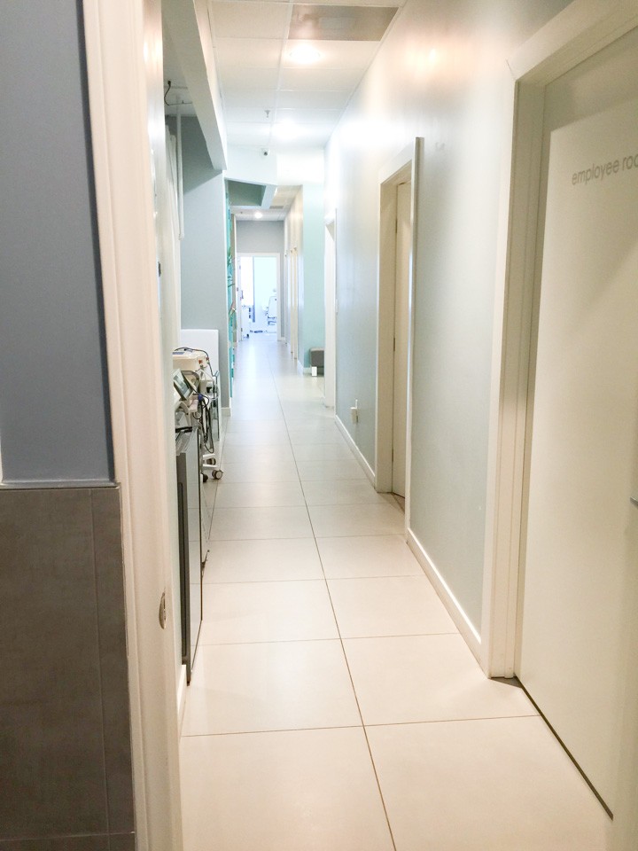 A hallway with white tile floors and walls.