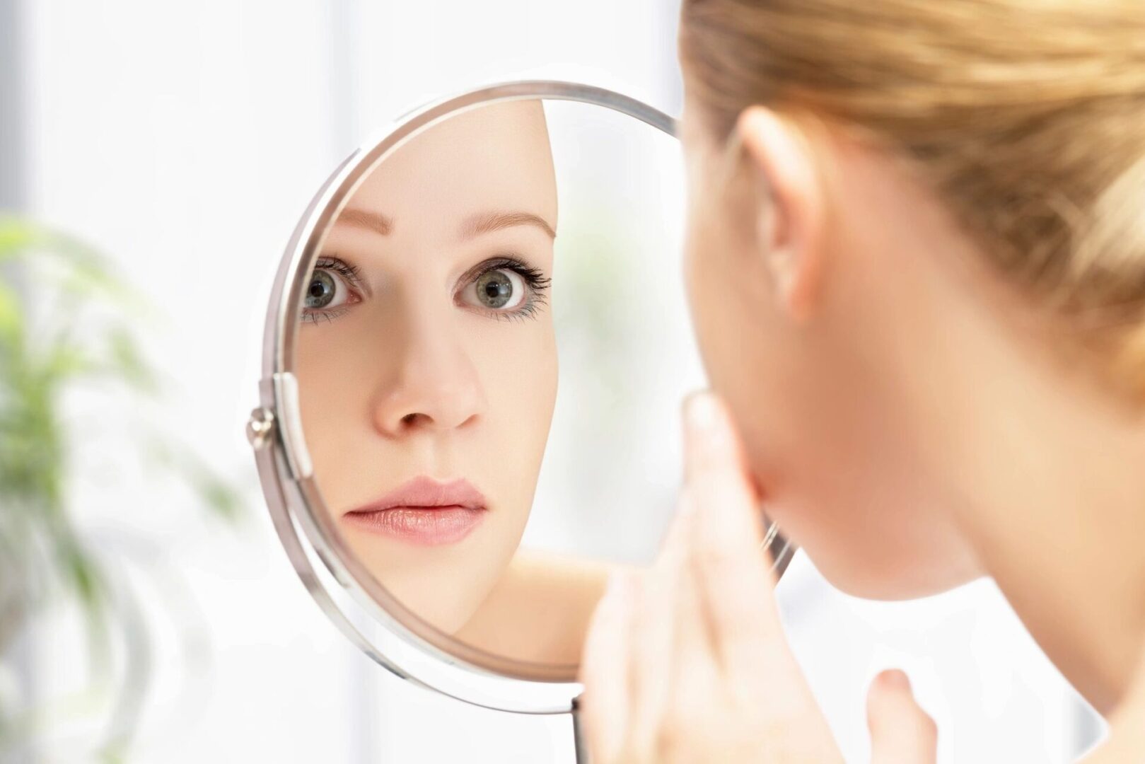 A woman looking at her reflection in the mirror.