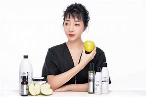 A woman holding an apple in front of some beauty products.